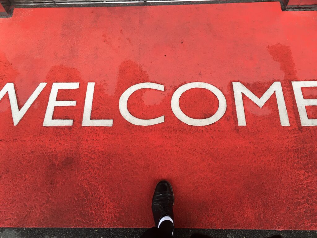 Ein Fuss betritt einen roten Teppich mit der Aufschrift Welcome – Aufbruch und Begleitung bei Trauer und Verlust, Christine Süssmann Basel